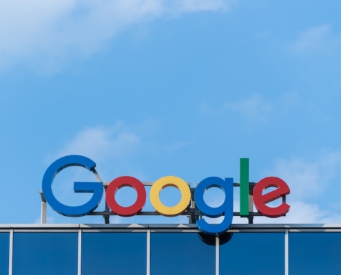 A "Google" sign on top of a building in front of a blue sky