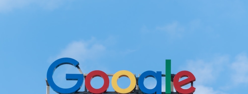 A "Google" sign on top of a building in front of a blue sky