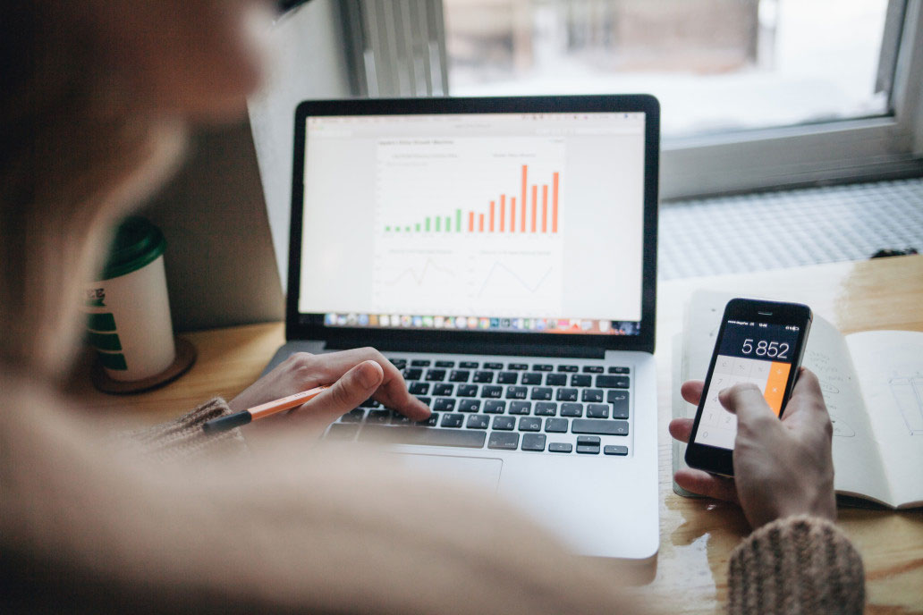Person analyzing business growth on laptop & phone